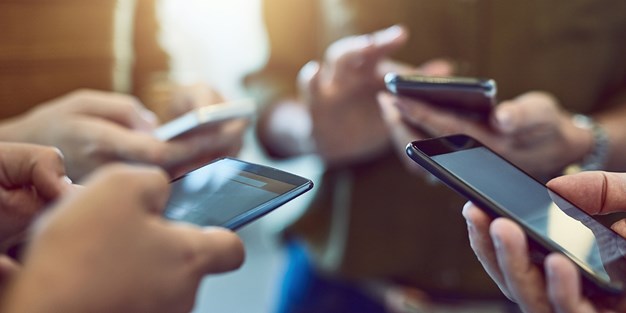 Ett antal personer som håller i var sin smartphone. Foto