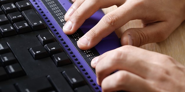 A person reading braille display. Photo.