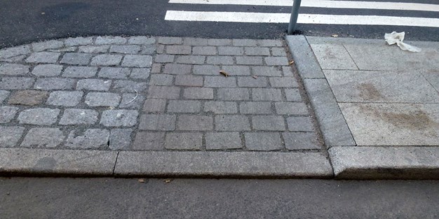 En mindre kant vid en trottoar och övergångsställe. Foto