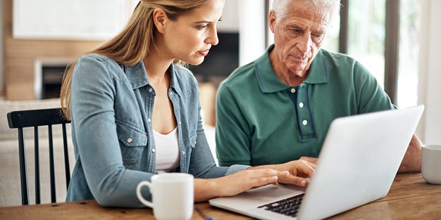 Två personer som arbetar vid en laptop. Foto