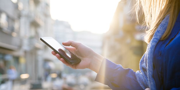 En hand som håller en mobiltelefon, foto.