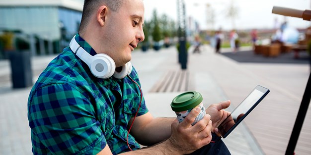 En tonåring med downs syndrom som använder en smartphone. Foto
